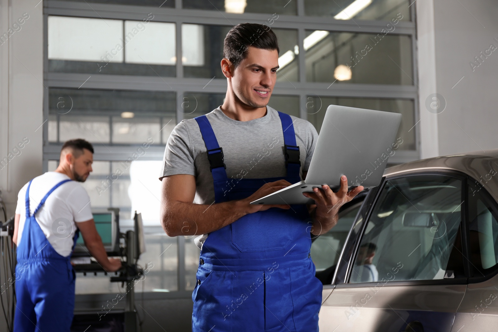 Photo of Mechanic with laptop doing car diagnostic at automobile repair shop