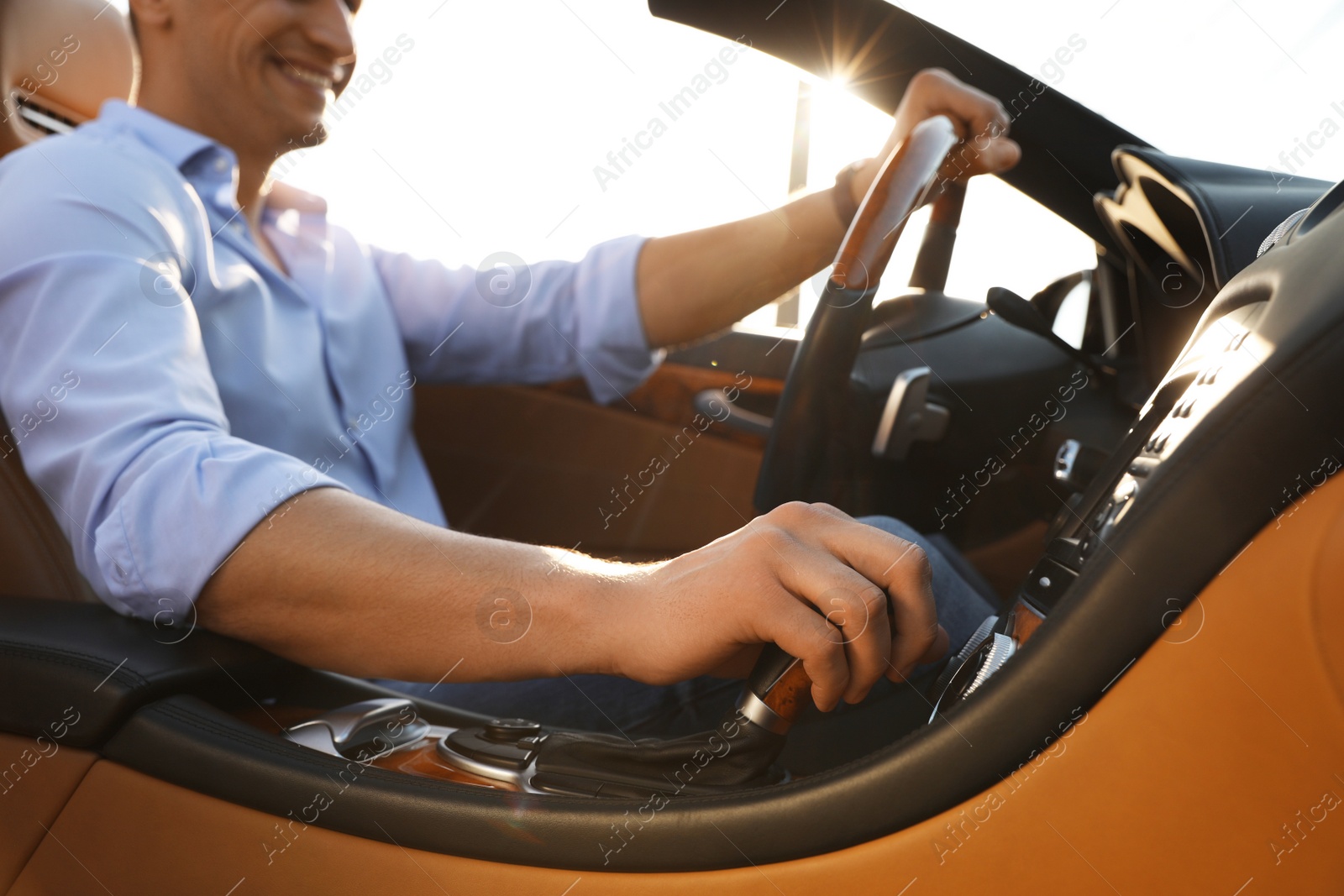 Photo of Businessman driving luxury convertible car outdoors, closeup