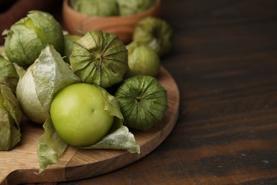 Fresh green tomatillos with husk on wooden table, closeup. Space for text