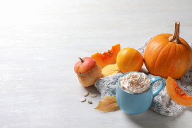 Photo of Cup with pumpkin spice latte, autumn decor and space for text on light table