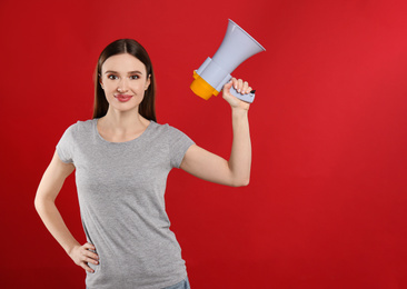 Photo of Young woman with megaphone on red background. Space for text