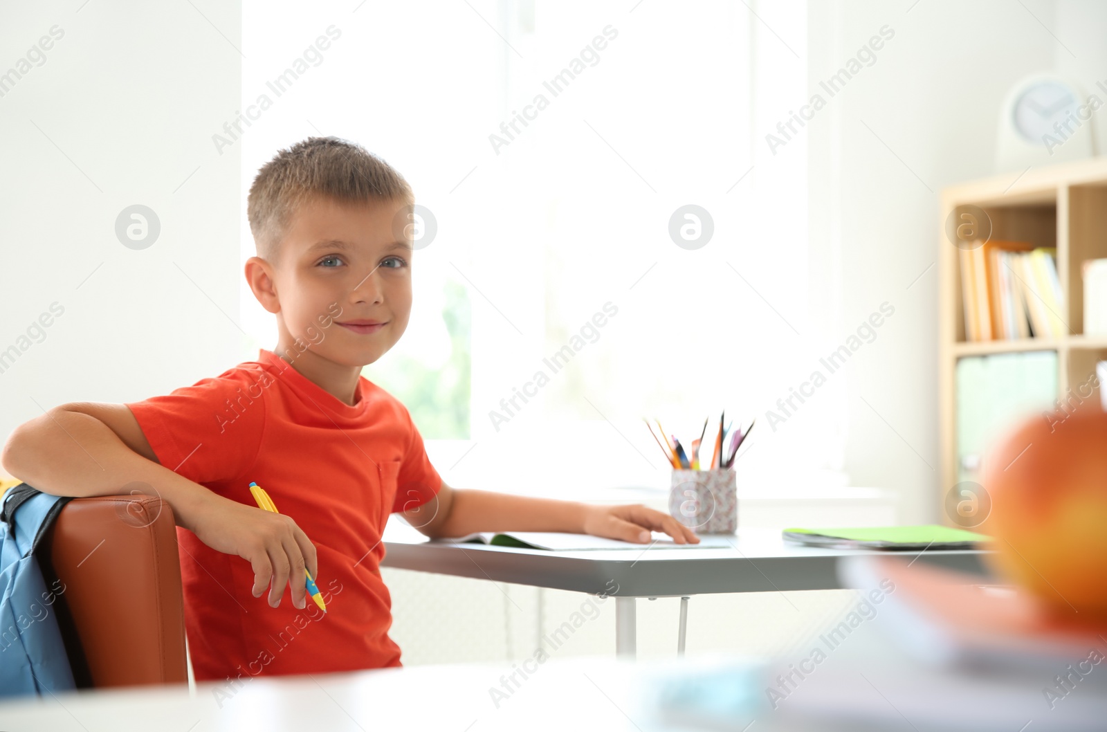 Photo of Cute little child sitting at desk in classroom. Elementary school