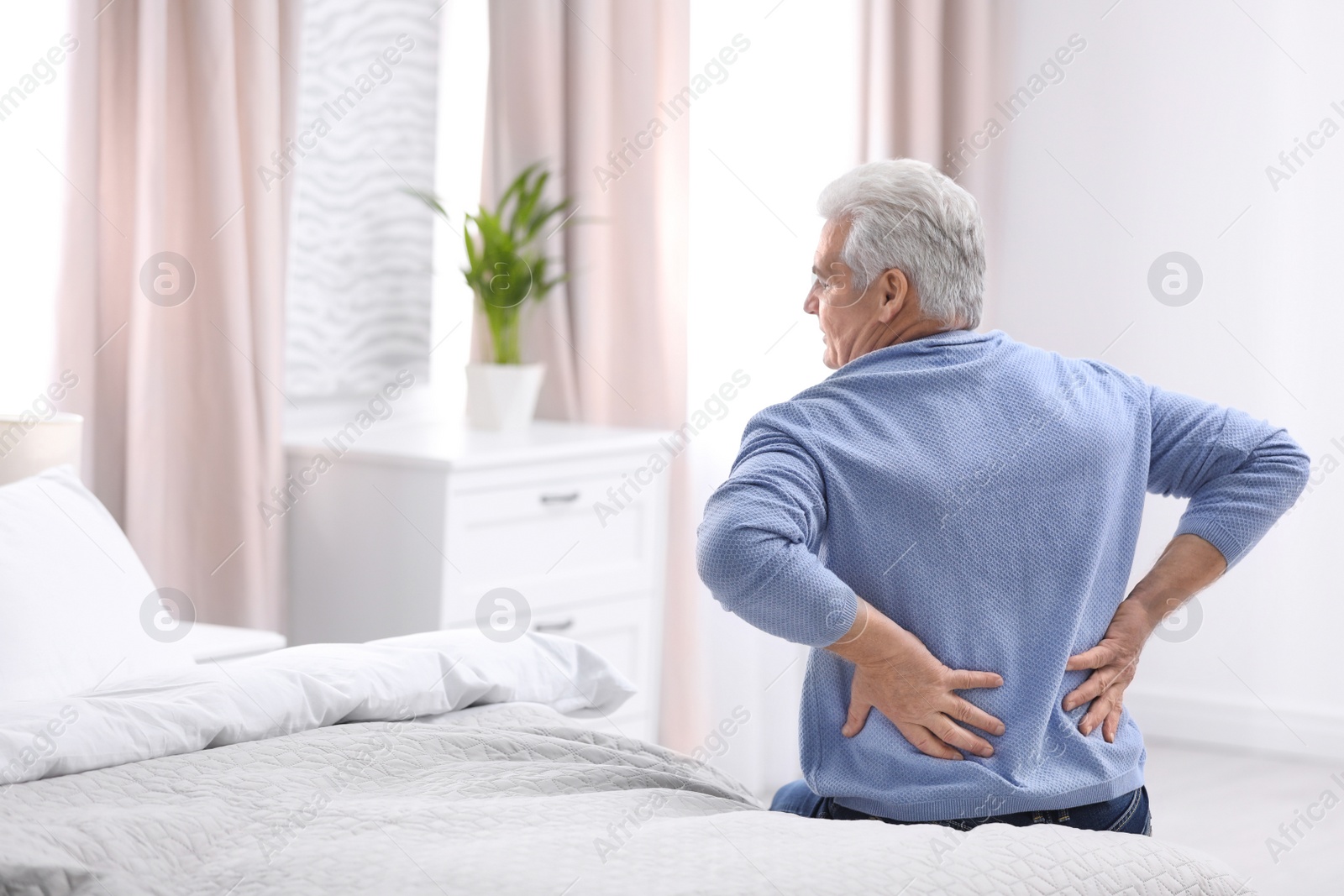 Photo of Senior man suffering from back pain at home