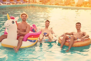 Image of Happy young friends relaxing in swimming pool