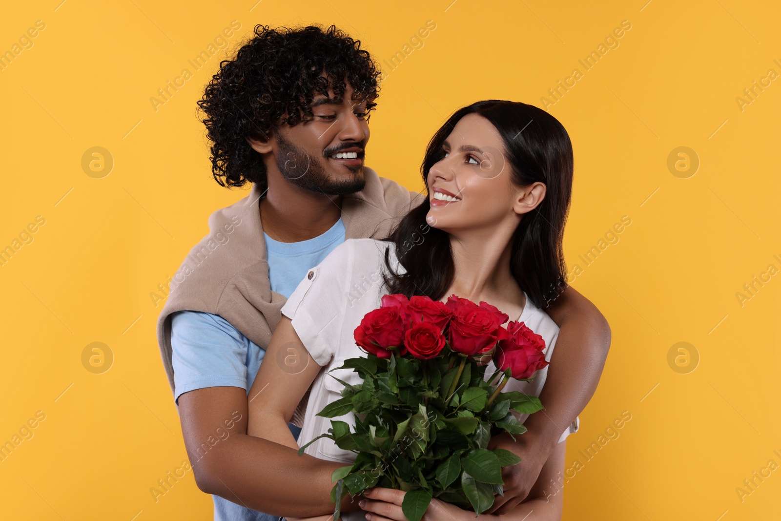 Photo of International dating. Happy couple with bouquet of roses on yellow background