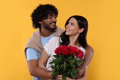 Photo of International dating. Happy couple with bouquet of roses on yellow background