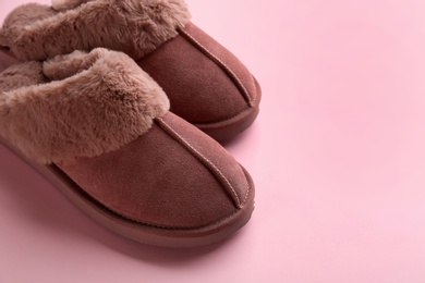 Photo of Pair of stylish soft slippers on pink background, closeup. Space for text