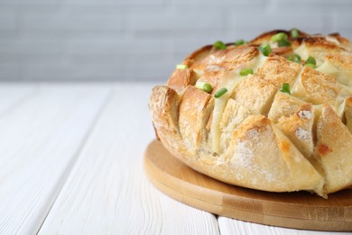 Photo of Freshly baked bread with tofu cheese and green onions on white wooden table, closeup. Space for text