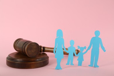 Paper family figure and wooden gavel on pink background. Child adoption concept
