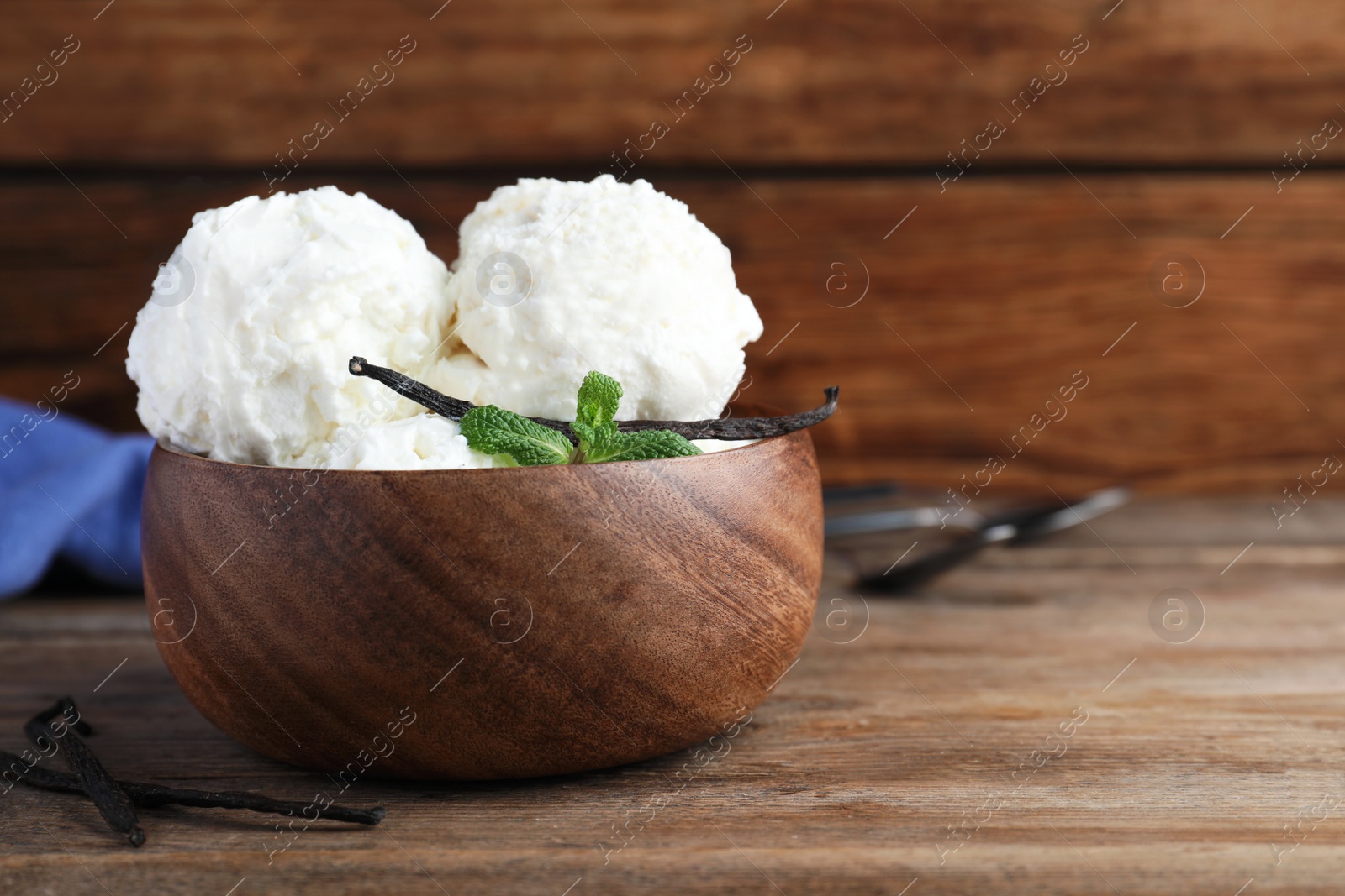 Photo of Yummy vanilla ice cream in bowl on wooden table. Space for text