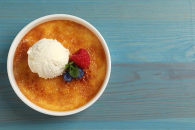 Photo of Delicious creme brulee with scoop of ice cream, fresh berries and mint on light blue wooden table, top view. Space for text