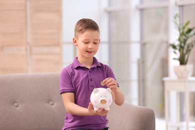 Photo of Little boy with piggy bank and money at home