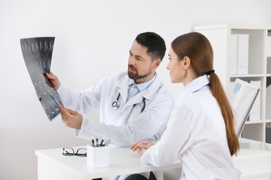 Orthopedists examining X-ray picture at desk in clinic