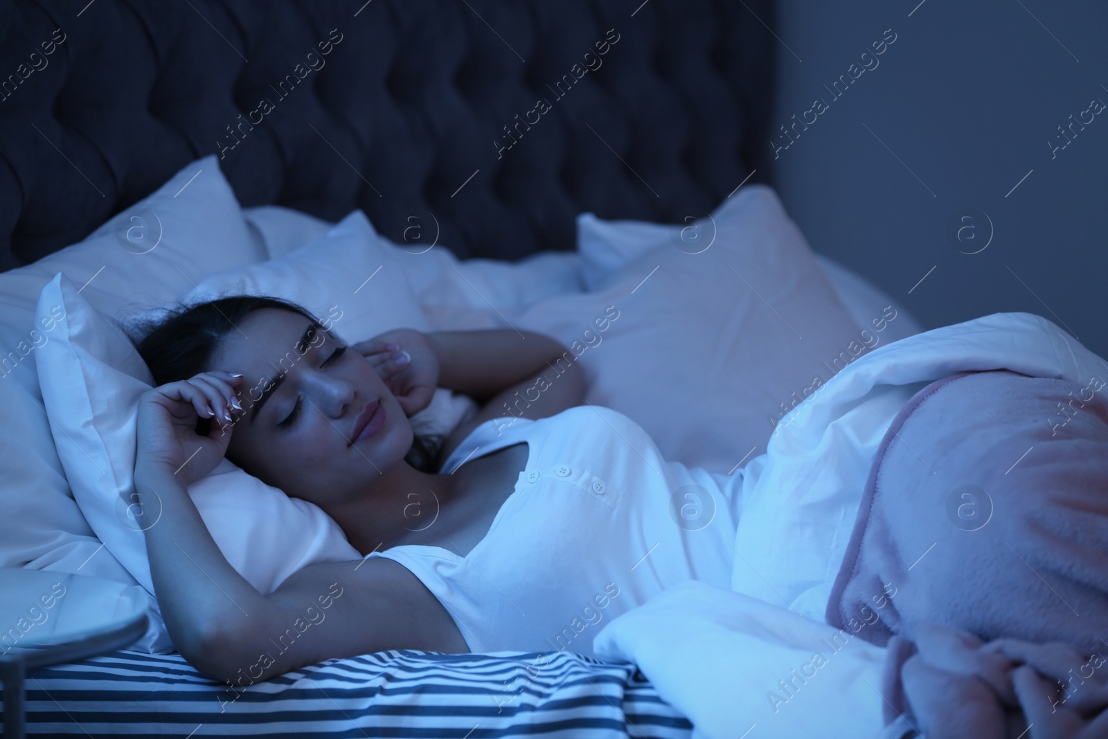 Photo of Young woman sleeping in bed at night. Sleeping time