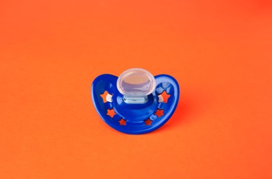 Photo of One blue baby pacifier on orange background
