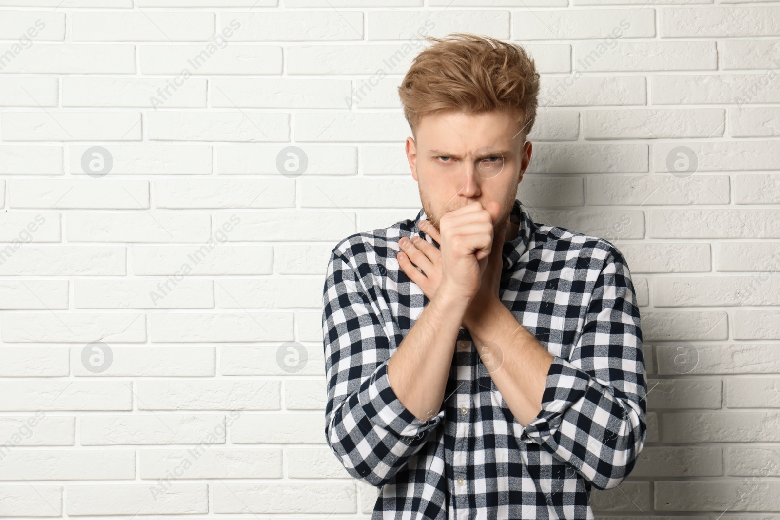 Photo of Handsome young man coughing near brick wall. Space for text