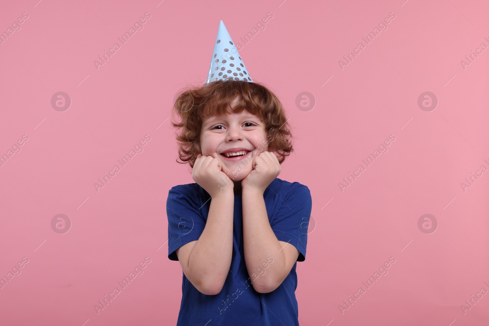 Photo of Happy little boy in party hat on pink background