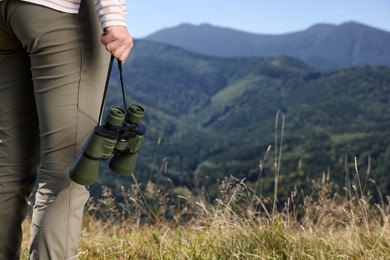 Photo of Woman with binoculars in mountains on sunny day, closeup