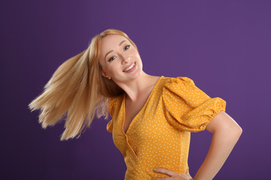 Photo of Beautiful young woman with blonde hair on purple background