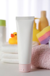 Tube of baby care product and towels on white table indoors