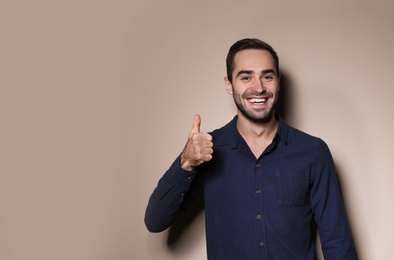 Photo of Man showing THUMB UP gesture in sign language on color background, space for text