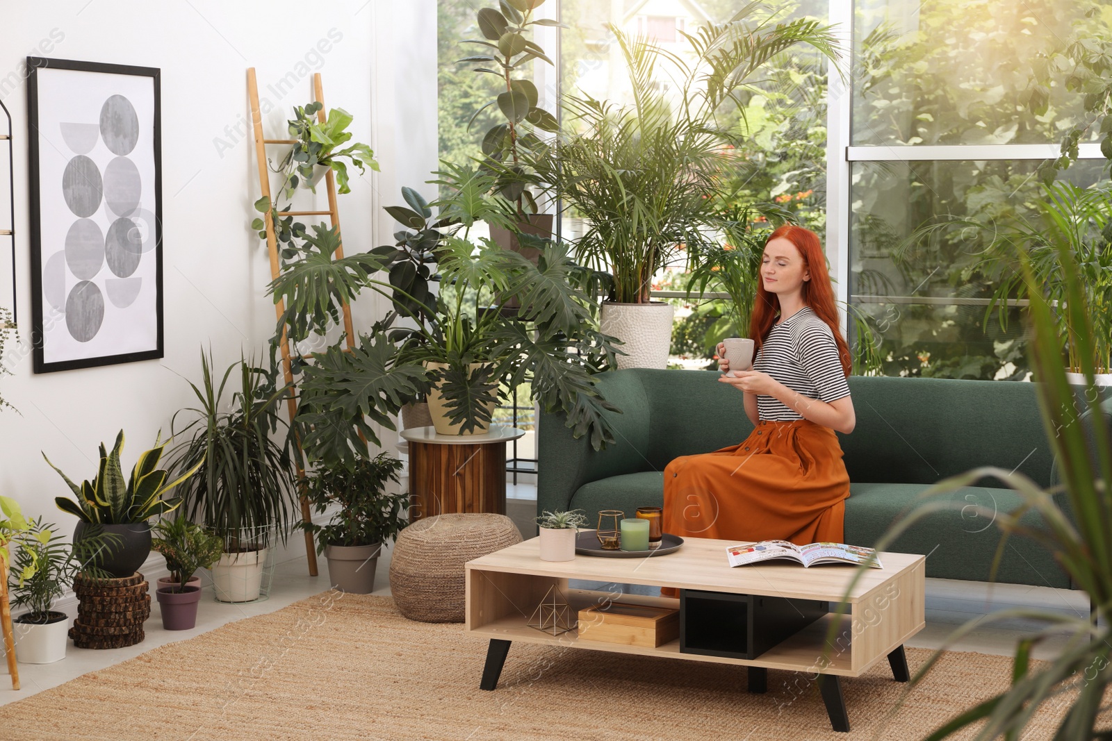 Photo of Beautiful woman with cup of tea resting on sofa in room