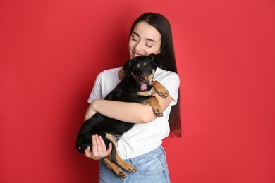 Young woman with cute puppy on red background