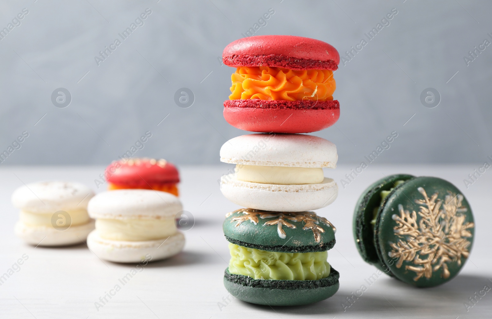 Photo of Different decorated Christmas macarons on white table, closeup