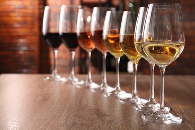 Different tasty wines in glasses on wooden table