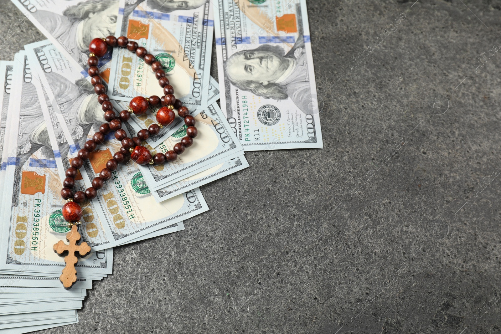 Photo of Wooden cross and money on grey table, space for text
