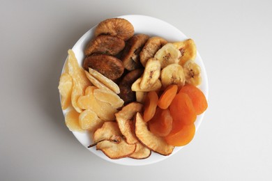 Bowl of different dried fruits on white background, top view