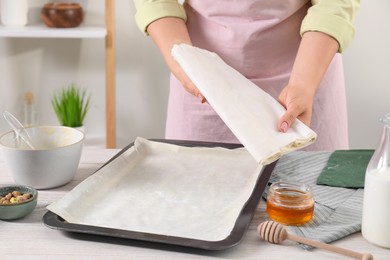 Woman making delicious baklava at white wooden table, closeup