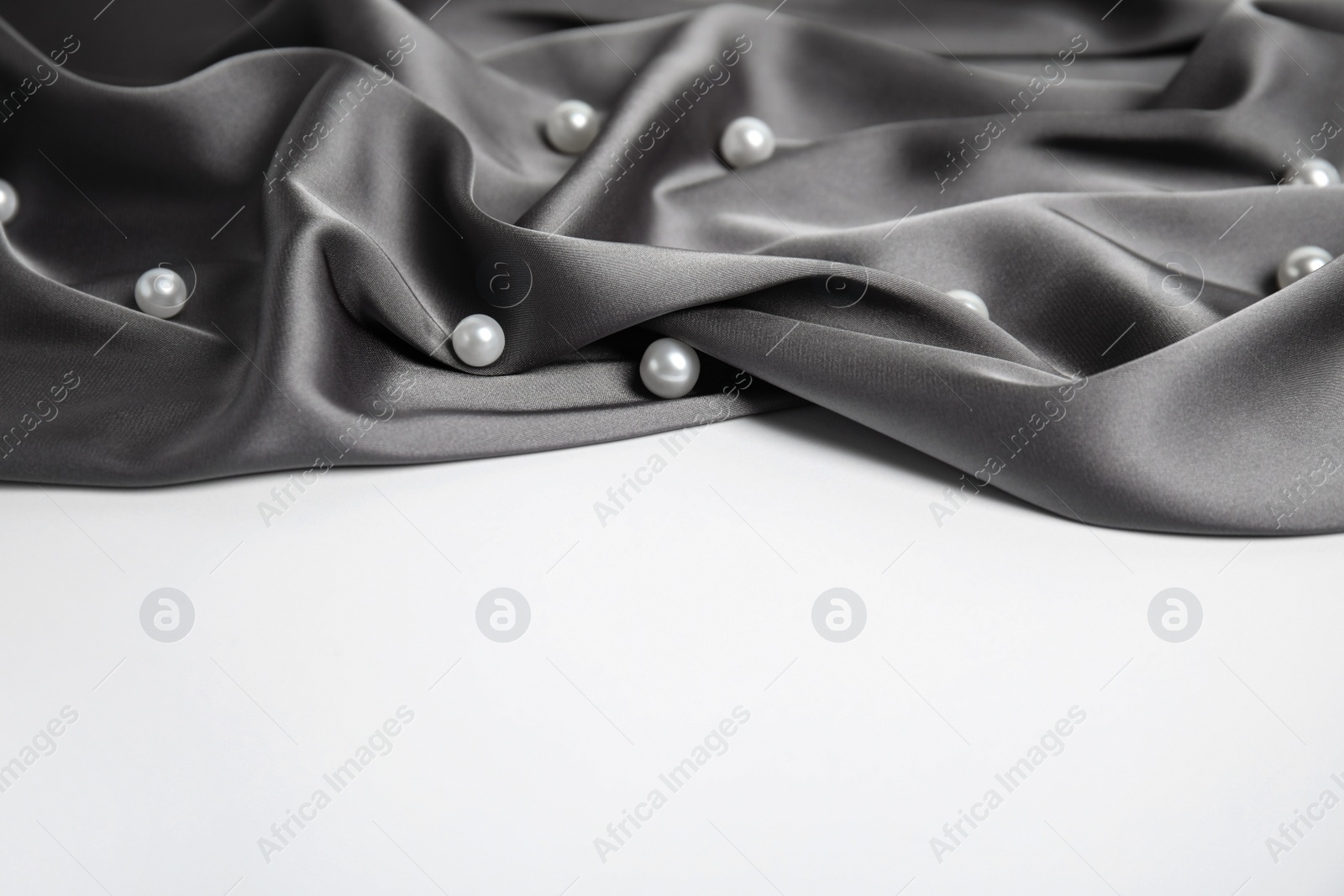 Photo of Texture of delicate black silk with pearls on white background