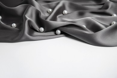 Photo of Texture of delicate black silk with pearls on white background