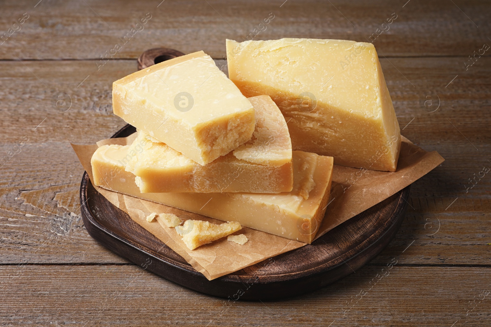 Photo of Pieces of delicious parmesan cheese on wooden table