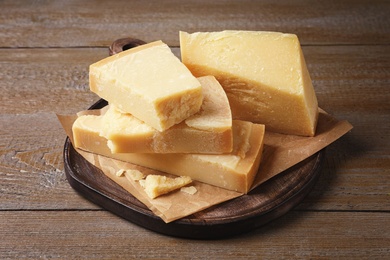 Photo of Pieces of delicious parmesan cheese on wooden table