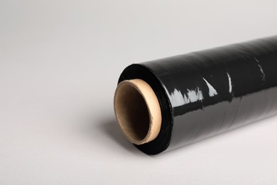 Photo of Roll of black stretch wrap on light grey background, closeup. Space for text