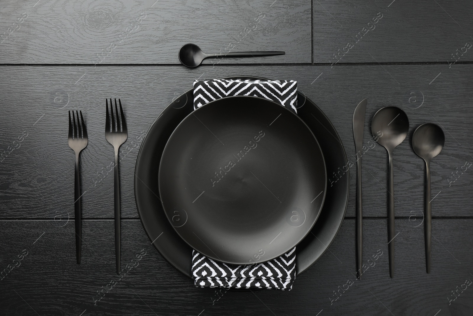 Photo of Stylish setting with cutlery and plates on black wooden table, flat lay