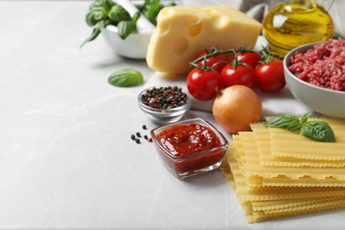 Fresh ingredients for lasagna on light grey marble table