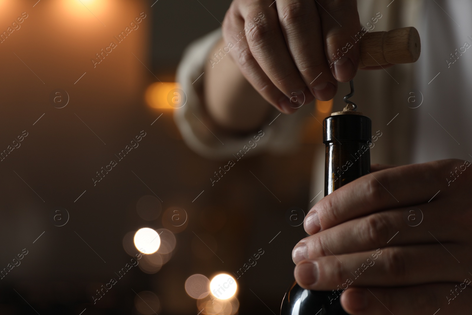 Photo of Man opening wine bottle with corkscrew on blurred background, closeup. Space for text