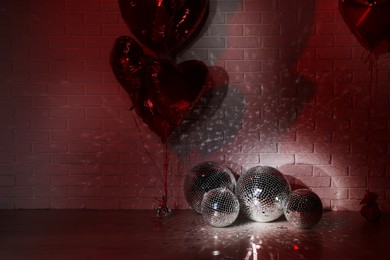 Many shiny disco balls in room decorated with heart shaped balloons, color toned