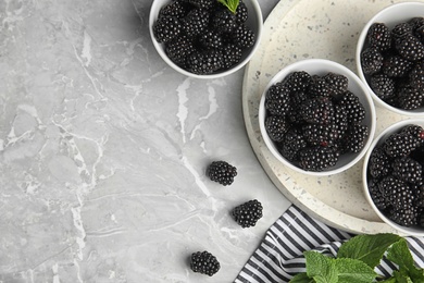 Photo of Flat lay composition of tasty blackberries and space for text on grey marble table