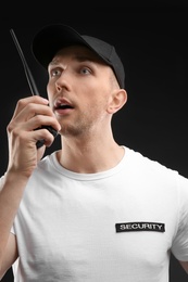 Male security guard using portable radio transmitter on dark background