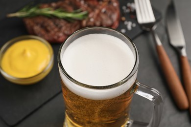 Mug of tasty beer on table, closeup view