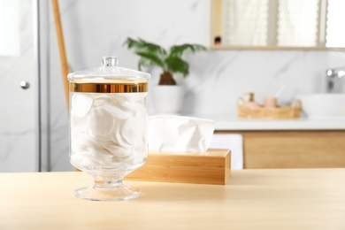 Photo of Jar with cotton pads on table in bathroom