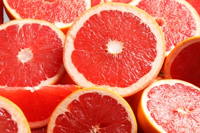 Photo of Many sliced fresh ripe grapefruits as background, closeup