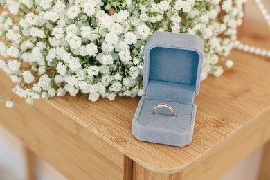 Photo of Box with engagement ring and beautiful bouquet on wooden table. Wedding day