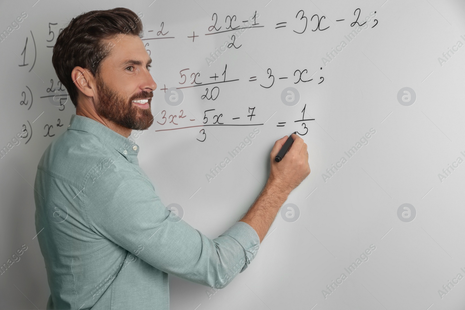 Photo of Happy teacher explaining mathematics at whiteboard in classroom