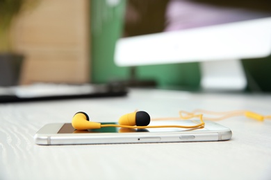 Photo of Smartphone with headphones on white table. Space for text