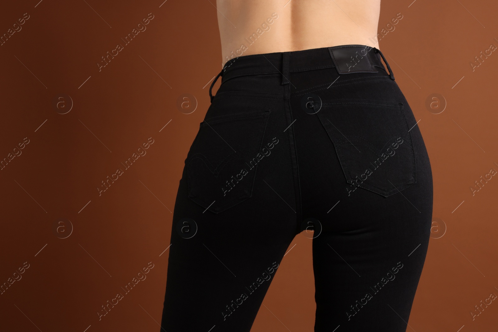 Photo of Woman wearing stylish black jeans on brown background, closeup. Space for text